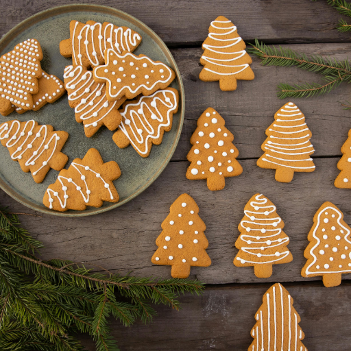 Hands icing Christmas cookies with red and green frosting during holiday cookie decorating.